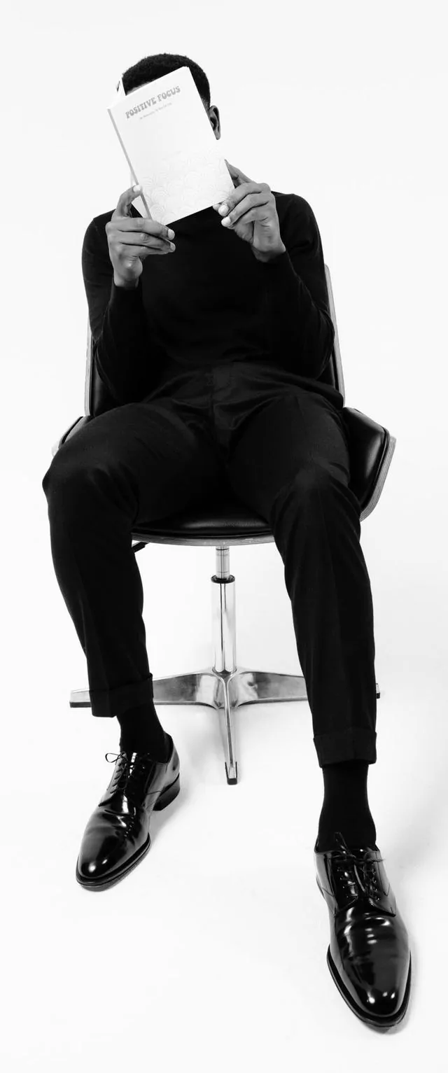 Samy Samandjeu seated, reading his book Positive Focus